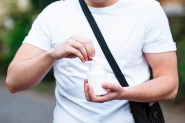 Yetişkin bir kadın beyaz arka planda beyaz plastik şişeyle hap dolduruyor. Yetişkinlerde sağlık hizmeti. Hipnoz ve uykusuzluk kavramı.