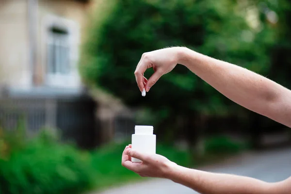 大人の女性が背景に隔離された手に白いプラスチックボトルで錠剤を注ぐ手 大人の健康管理 催眠術と不眠症の概念 — ストック写真