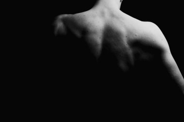 Kas büyüsü ve insanın arkası. Kas gösterisi. Alçakgönüllülük. Siyah beyaz fotoğraf. Kaslı, seksi vücutlu ve sırtı açık bir erkek model..