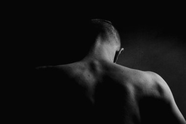 Kas büyüsü ve insanın arkası. Kas gösterisi. Alçakgönüllülük. Siyah beyaz fotoğraf. Kaslı, seksi vücutlu ve sırtı açık bir erkek model..