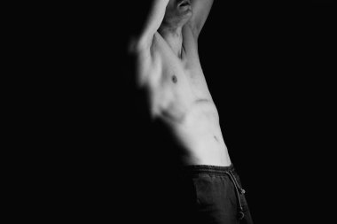 Güçlü atletik adam, vücut geliştirici. Tanınmaz halde, yüz resmi yok. Çıplak gövde, kaslı vücut. Güçlü göğüs ve omuz kasları. Siyah arka planda stüdyo çekimi, sade anahtar. Vücut geliştirme kavramı