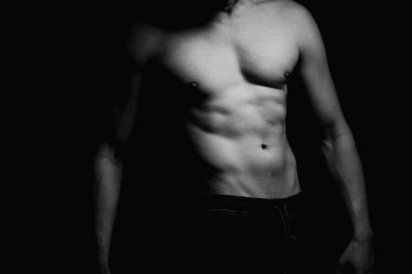 Güçlü atletik adam, vücut geliştirici. Tanınmaz halde, yüz resmi yok. Çıplak gövde, kaslı vücut. Güçlü göğüs ve omuz kasları. Siyah arka planda stüdyo çekimi, sade anahtar. Vücut geliştirme kavramı