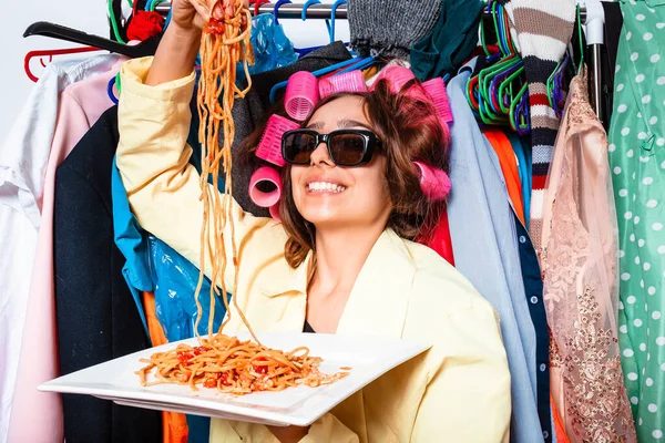 Kıvırcık elbiseli kız, makarna ve çatallı tabak ketçaplı makarna yiyor ve beyaz arka planda gözlüklü duruyor. Spagetti yiyen kız. Elinde bir tabak makarna tutan kız..