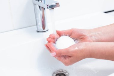 Koronavirüs virüslerini önlemek için insan sabunu ve suyla el yıkama, koronavirüsün yayılmasını engellemek için hijyen. Kadın sabun kullanıyor ve ellerini musluğun altında yıkıyor. El hijyeni konsepti ayrıntıları.