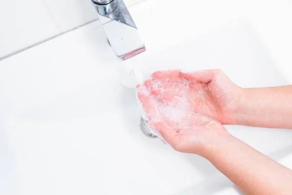 Koronavirüs virüslerini önlemek için insan sabunu ve suyla el yıkama, koronavirüsün yayılmasını engellemek için hijyen. Kadın sabun kullanıyor ve ellerini musluğun altında yıkıyor. El hijyeni konsepti ayrıntıları.