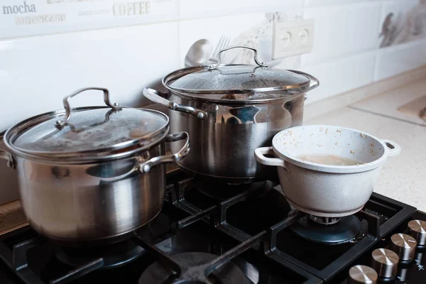 Utensils for cooking classes on stove in kitchen. Metal pans on kitchen counter. Female chef cooking in restaurant kitchen.