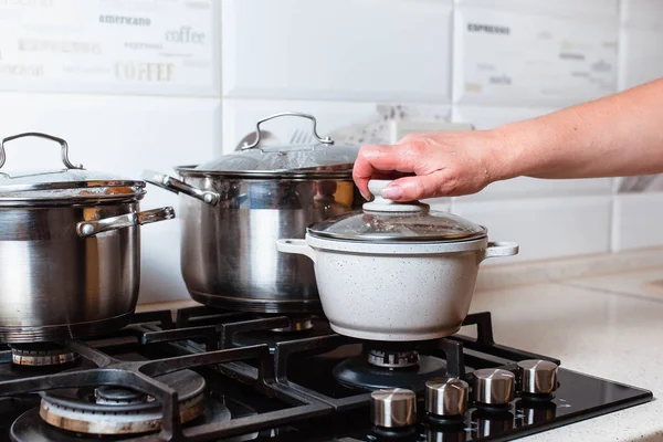 Utensils for cooking classes on stove in kitchen. Metal pans on kitchen counter. Female chef cooking in restaurant kitchen.