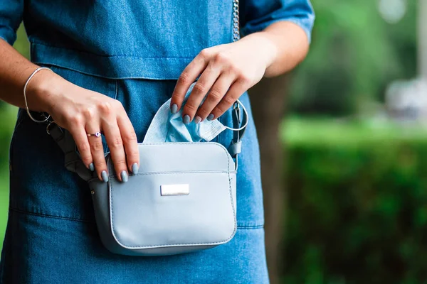 Medical mask in a womans bag. The girl gets a mask from handbag. A handbag with protective equipment