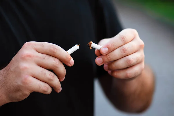 World No Smoking Day. The fight against nicotine addiction. The guy breaks a cigarette. Male hand crushing cigarette. Concept Quitting smoking, World No Tobacco Day. No Smoking.
