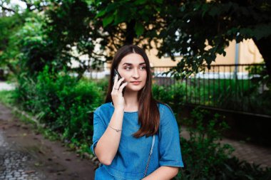 Cep telefonuyla konuşuyorum. Mutlu ve kendinden emin gülümseyen genç ve güzel bir kadın. Yüzünde gülümsemeyle şehrin akıllı telefonuyla konuşuyor..