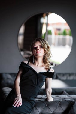 Güzel sarışın, genç kız. Restorandaki genç bir kızın portresi. Siyah arka planda bir restoranda genç bir kız. Siyah elbiseli bir kızın portresi. Genç kız..