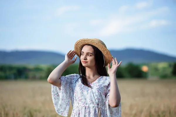 Buğday tarlasında bir kızın portresi. Buğday tarlasında beyaz elbiseli ve şapkalı güzel bir kızın portresi. Beyaz elbiseli ve şapkalı kız. Buğday tarlası. Doğada genç bir kadının portresi..