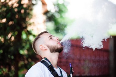 Genç yakışıklı adam tek başına nargile içiyor. Genç adam nargile içiyor. Nargile ve kömürden kıvılcımlar. Shisha, kıvılcım, nargile kıvılcımı. Genç adam güzel kokulu doğu nargilesi içiyor..