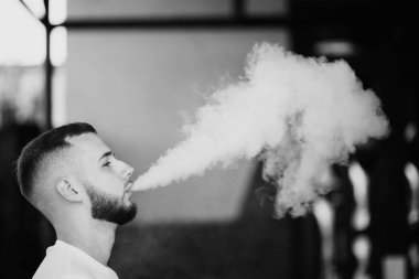 Genç yakışıklı adam tek başına nargile içiyor. Genç adam nargile içiyor. Nargile ve kömürden kıvılcımlar. Shisha, kıvılcım, nargile kıvılcımı. Genç adam güzel kokulu doğu nargilesi içiyor..