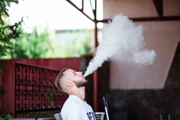 Young handsome guy smoking hookah alone closeup. Young guy smoking a hookah. Hookah and sparks from coals. Shisha, spark, hookah sparks. Young man smokes a fragrant oriental hookah.