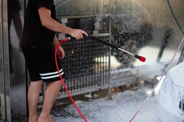 Yaz araba yıkama. Arabayı yüksek basınçlı suyla temizliyorum. Sabunla araba yıka. Konsepti kapat. Bir adamın yakın plan fotoğrafı arabasını yıkar. Dezenfeksiyon ve antiseptik temizliği hariç. Araba yıkama.