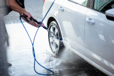 Yaz araba yıkama. Arabayı yüksek basınçlı suyla temizliyorum. Sabunla araba yıka. Konsepti kapat. Bir adamın yakın plan fotoğrafı arabasını yıkar. Dezenfeksiyon ve antiseptik temizliği hariç. Araba yıkama.