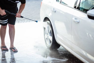 Yaz araba yıkama. Arabayı yüksek basınçlı suyla temizliyorum. Sabunla araba yıka. Konsepti kapat. Bir adamın yakın plan fotoğrafı arabasını yıkar. Dezenfeksiyon ve antiseptik temizliği hariç. Araba yıkama.
