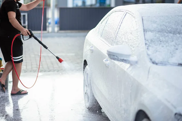 Summer car wash. Cleaning the car using high pressure water. Car wash with soap. Close up concept. Close up photo of a man hands washes his car Concept disinfection and antiseptic cleaning. Car wash.