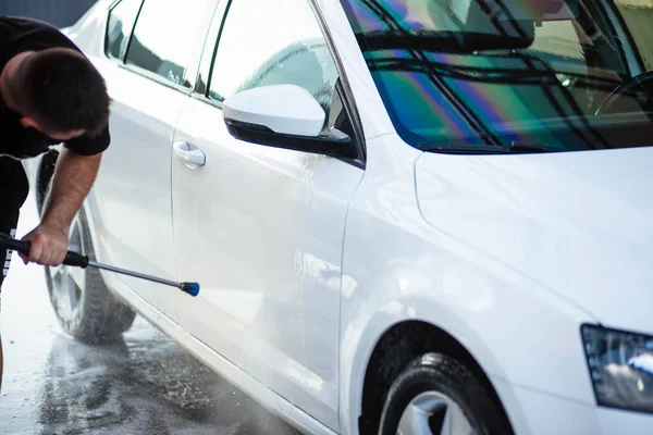 Summer car wash. Cleaning the car using high pressure water. Car wash with soap. Close up concept. Close up photo of a man hands washes his car Concept disinfection and antiseptic cleaning. Car wash.