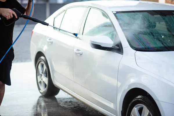 Summer car wash. Cleaning the car using high pressure water. Car wash with soap. Close up concept. Close up photo of a man hands washes his car Concept disinfection and antiseptic cleaning. Car wash.