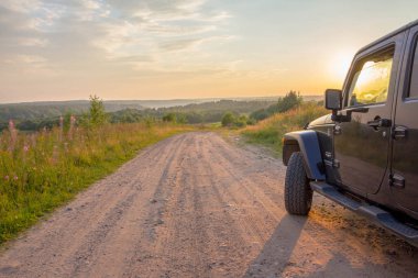 Leningrad region, Rusya Federasyonu, 27 Temmuz 2018: Jeep Wrangler akşam güneşin kırsal bir yolda. Wrangler kompakt dört tekerlekli arabayla yol ve spor yeni araç kapalı olduğunu