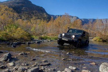 Kola Yarımadası. Murmansk bölgesi, Rusya, 8 Eylül 2018: Siyah Jeep Wrangler Sahara bir dağ nehir Murmansk bölgede hareket. Yol ve spor yeni araç