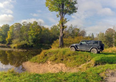 Novgorod bölgesi. Rusya, 22 Eylül 2018: Siyah Jeep Wrangler Sahara bir orman nehir kıyısında. Wrangler kompakt dört tekerlekli arabayla yol ve spor yeni araç kapalı olduğunu