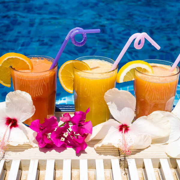 Three glasses of freshly squeezed exotic juice by the pool