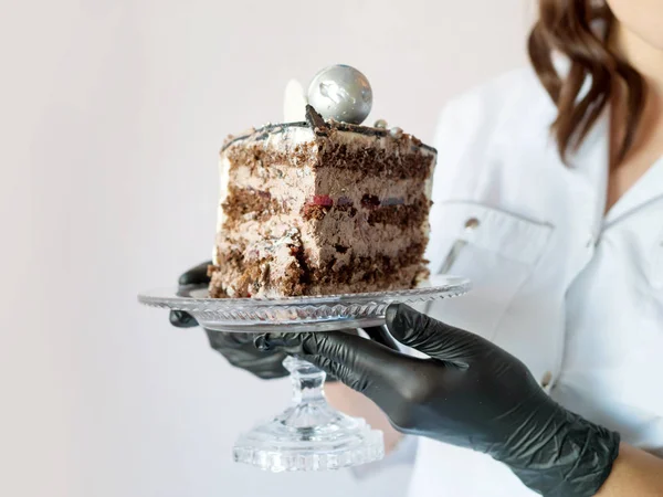 Le mani femminili tengono un pezzo di torta al cioccolato in un piatto. Pasticciere — Foto Stock