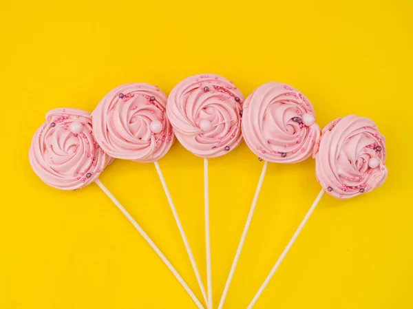 Pink meringue on a stick on a bright yellow background. meringue — Stock Photo, Image