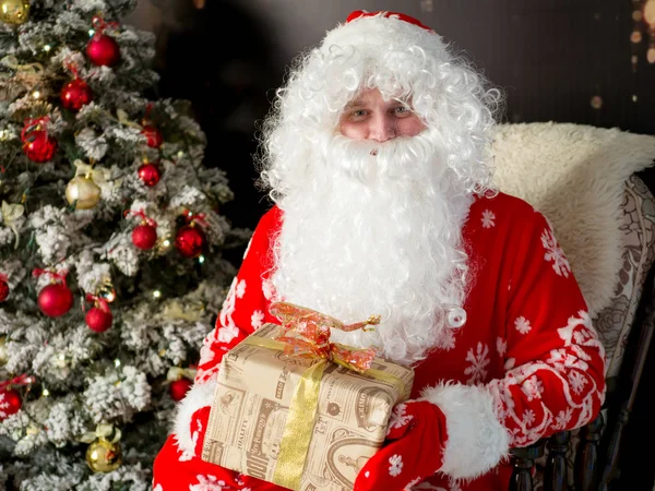 Mikołaja z prezent na Boże Narodzenie w jego ręce w pokoju z choinki. Boże Narodzenie i nowy rok — Zdjęcie stockowe