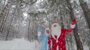 Noel Baba ve genç bir karlı çam ormanda ellerini sallayarak. Slow Motion Video