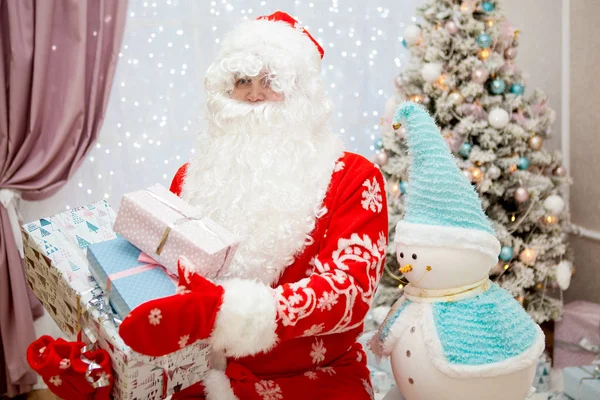 Retrato de Santa Claus con barba blanca y regalos en sus manos de cerca en el interior festivo de Año Nuevo — Foto de Stock