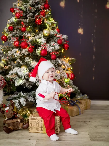 Küçük bebek Noel hediye ile Noel ağacı başına oturmuş — Stok fotoğraf