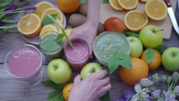 As mãos das mulheres tomam um copo com um batido na mesa da cozinha com frutas frescas. Dieta saudável — Vídeo de Stock