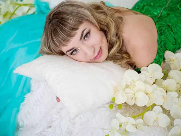 Well-groomed girl lying on a white pillow looking at the camera — Stock Photo, Image