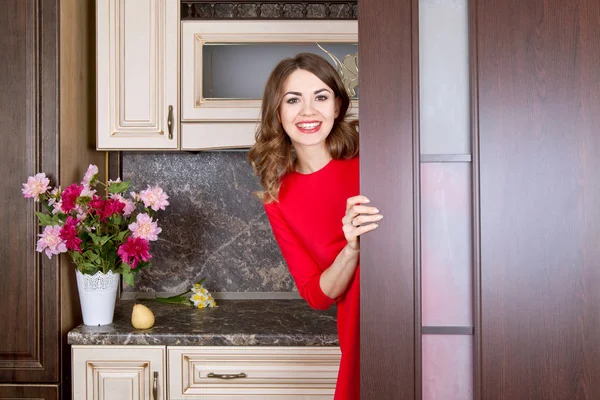 Glad tjej ser ut bakom dörren i köket — Stockfoto