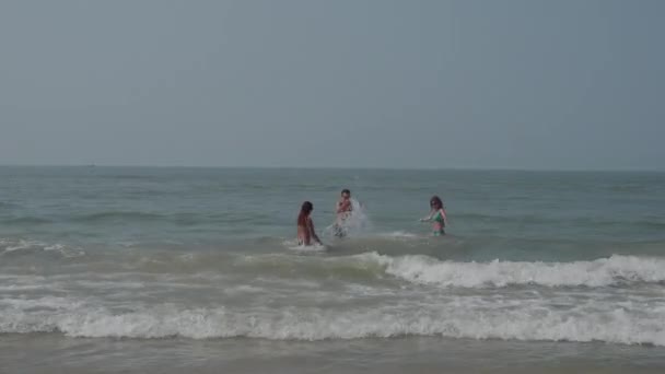 Egy fiatal férfi és két lány is vidáman locsolás egymást a tengerbe. Nyár, pihenés, hő. 4k — Stock videók