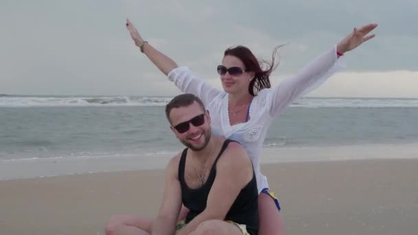 Красивая пара мужчина и девушка счастливо вместе отдыхают на берегу океана — стоковое видео