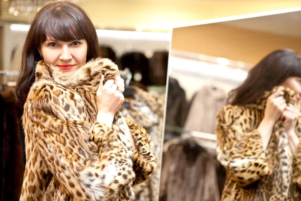 Beautiful woman in a boutique trying on a fur coat — Stock Photo, Image