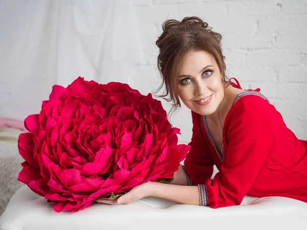 Red paper flower and portrait of a beautiful girl indoors — Stock Photo, Image