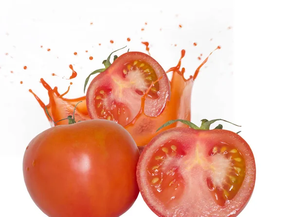 Saftige reife rote Tomaten und ein Spritzer Tomatensaft. isolieren — Stockfoto