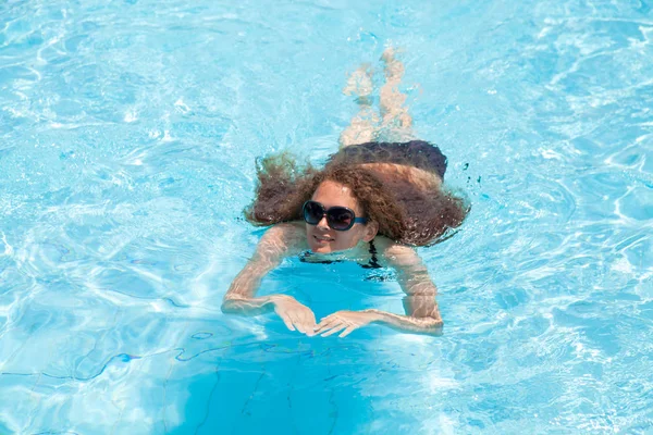 Молодая девушка плавает в бассейне в летний день — стоковое фото