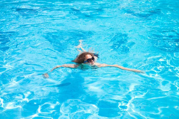 A menina nada na piscina em um dia quente de verão no resort . — Fotografia de Stock