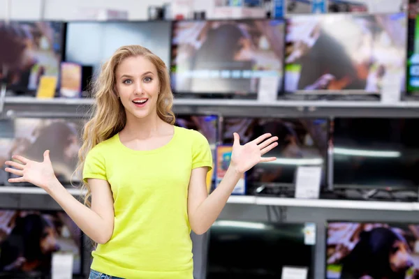 Genç güzel beyaz kız TV mağazasında kamera bakıyor — Stok fotoğraf