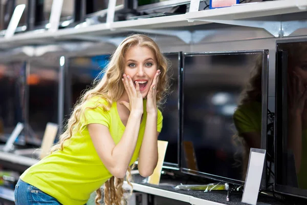Mooi meisje kiest een plasma-TV in de winkel — Stockfoto