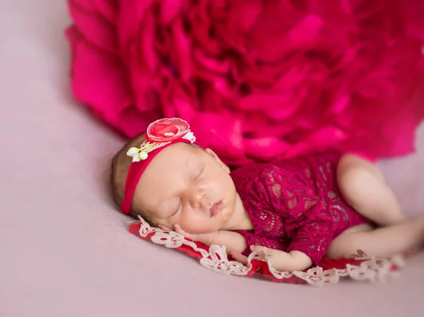 Little newborn baby in red bodysuit and with a red headband — Stock Photo, Image