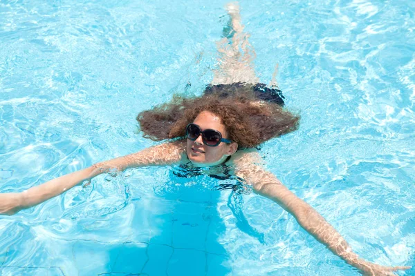 Молодая девушка плавает в бассейне в летний день на улице — стоковое фото