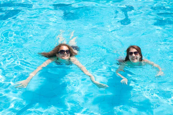 Duas garotas morenas nadam em férias na piscina — Fotografia de Stock